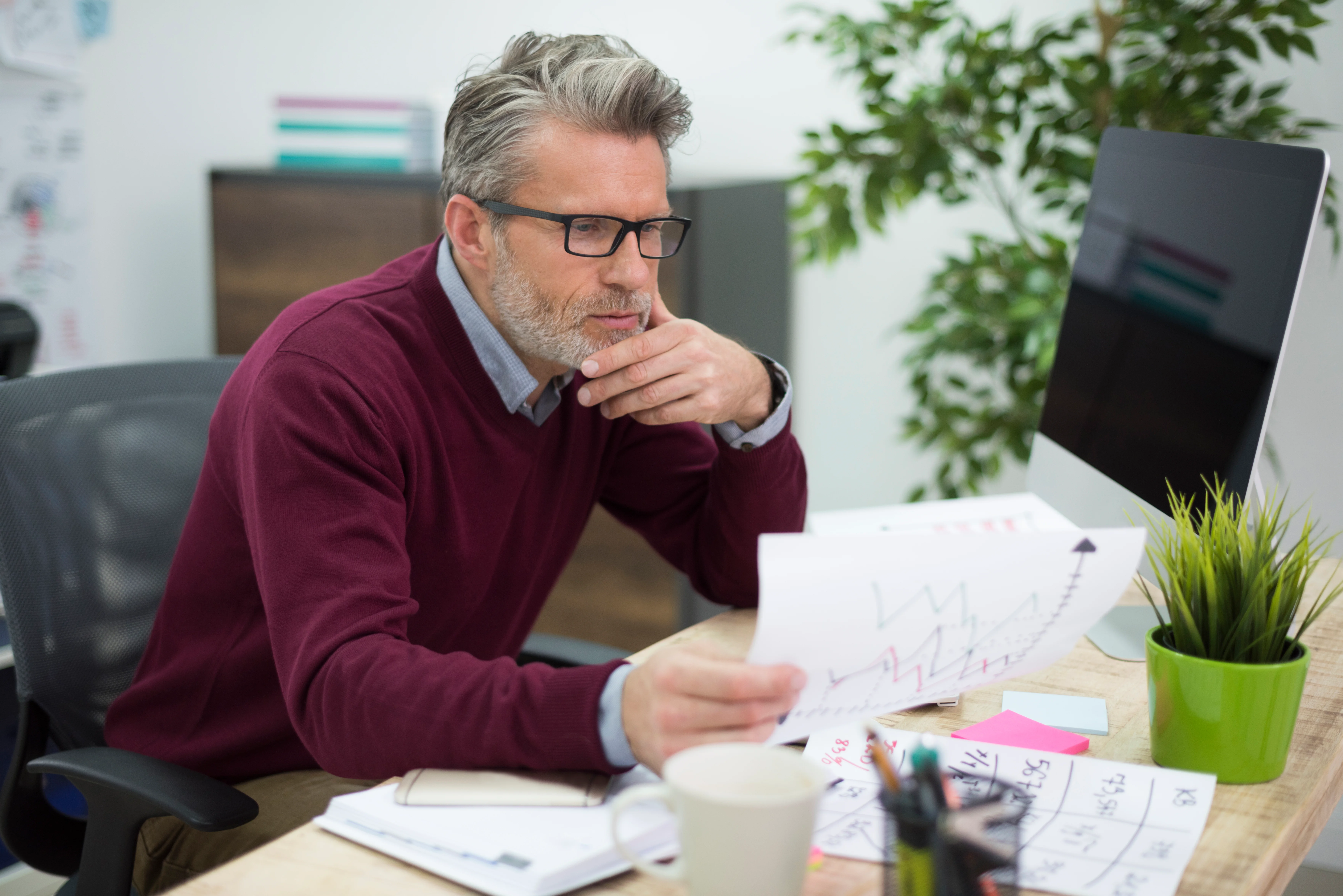 Businessman reviewing financial reports and investment charts while planning his finances