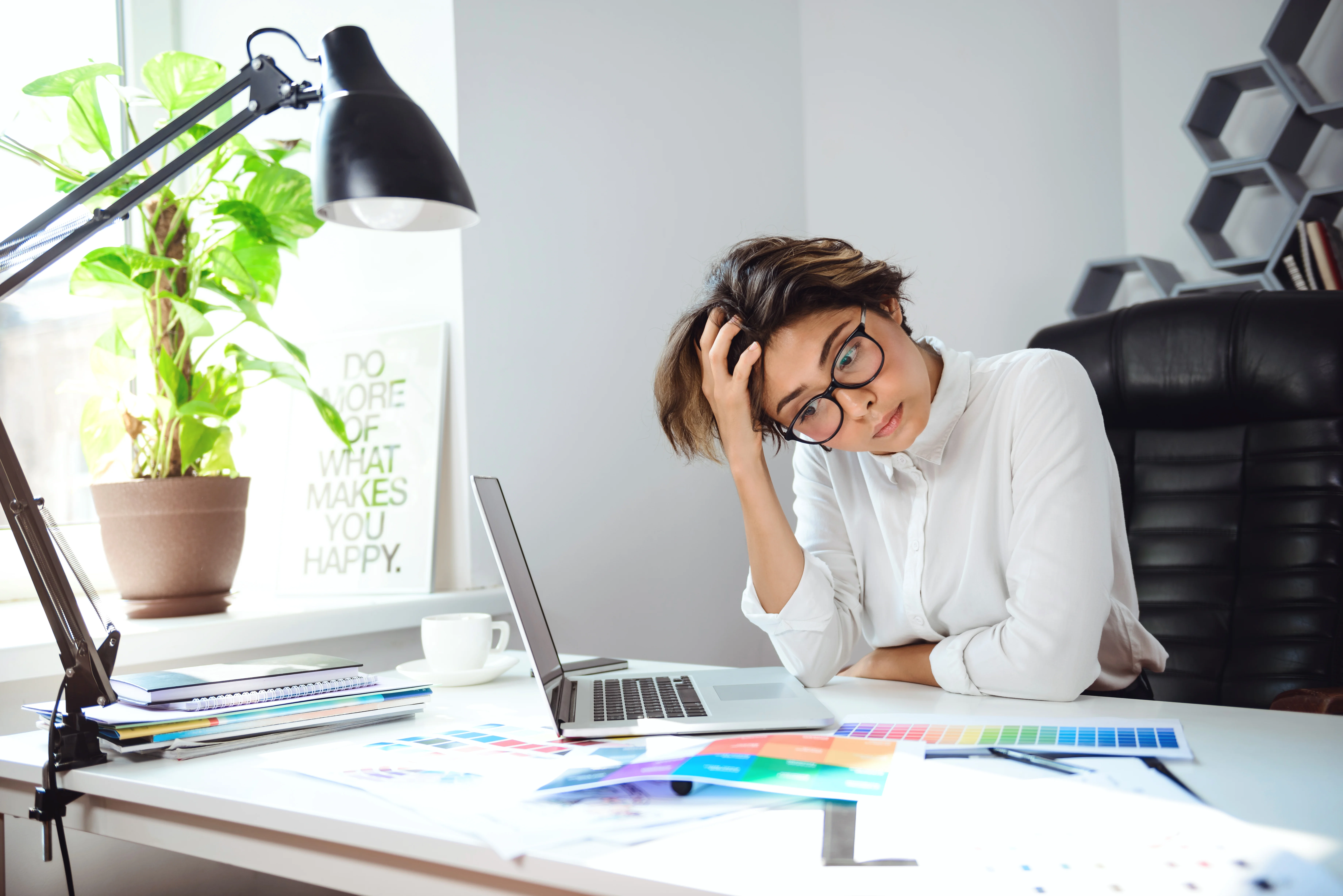 Businesswoman reviewing documents at her laptop while considering financial planning decisions