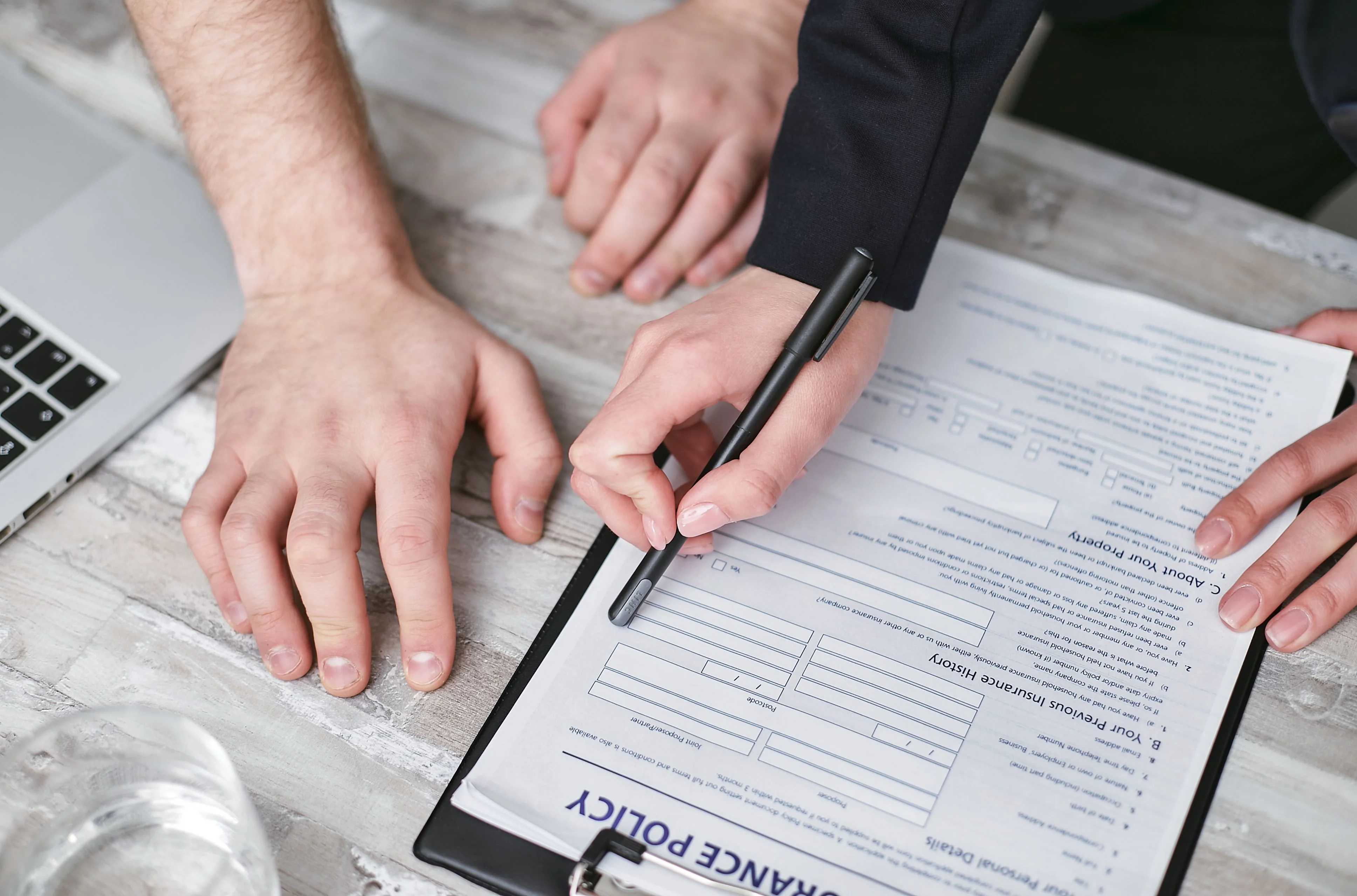 Close up of broker pointing to insurance paper explaining to client insurance paperwork