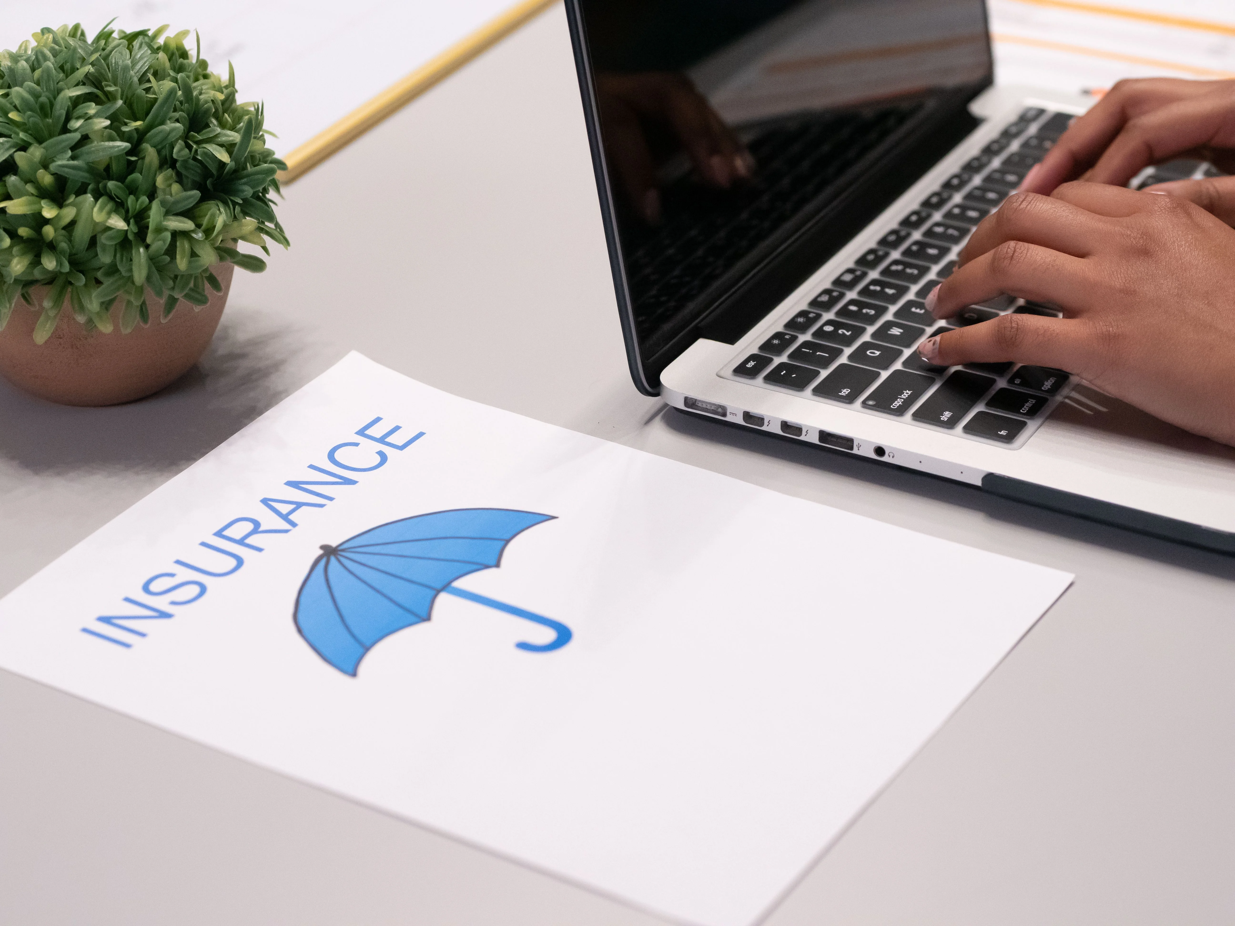 Close up of man on laptop at desk with insurance paper