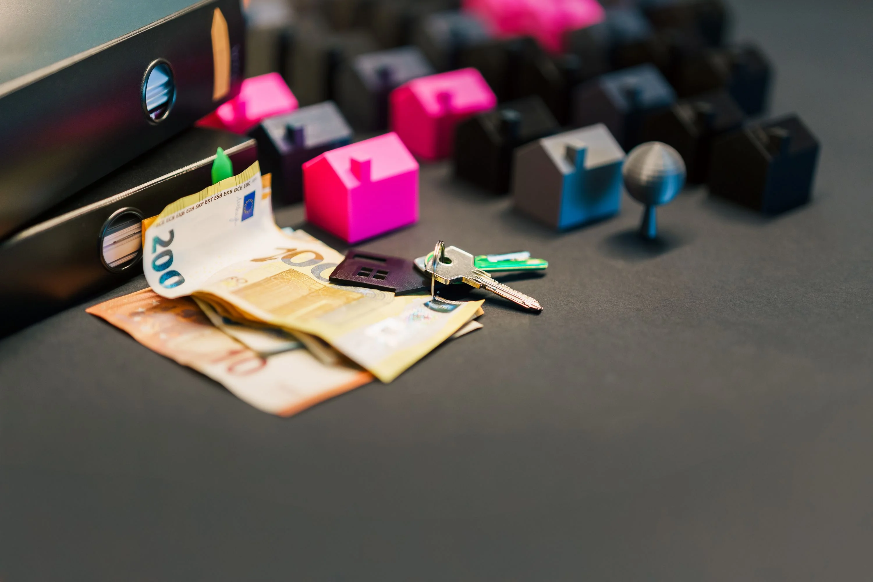 close up of money and house keys with rows of mini toy houses