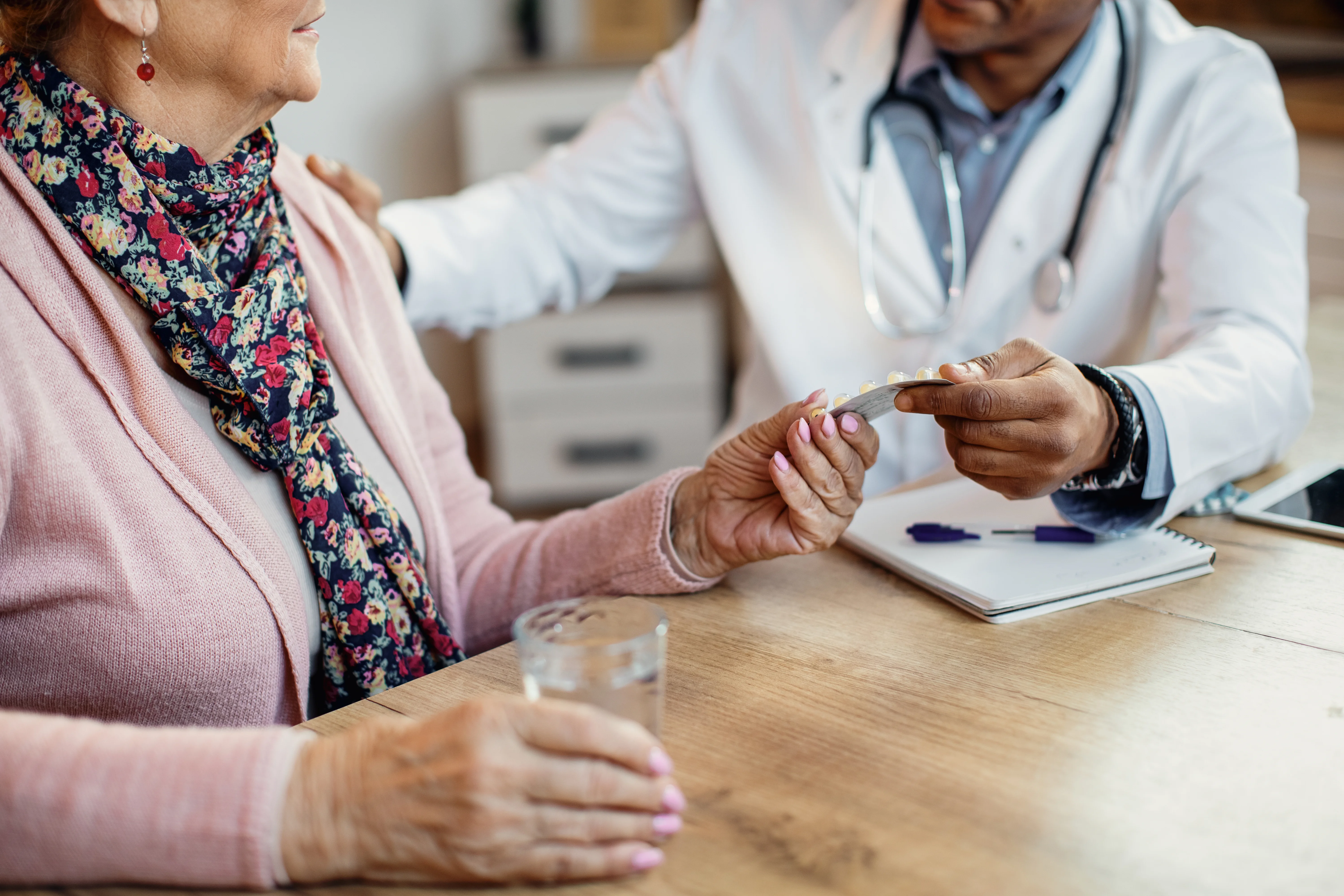 closeup doctor giving pills senior woman home visit