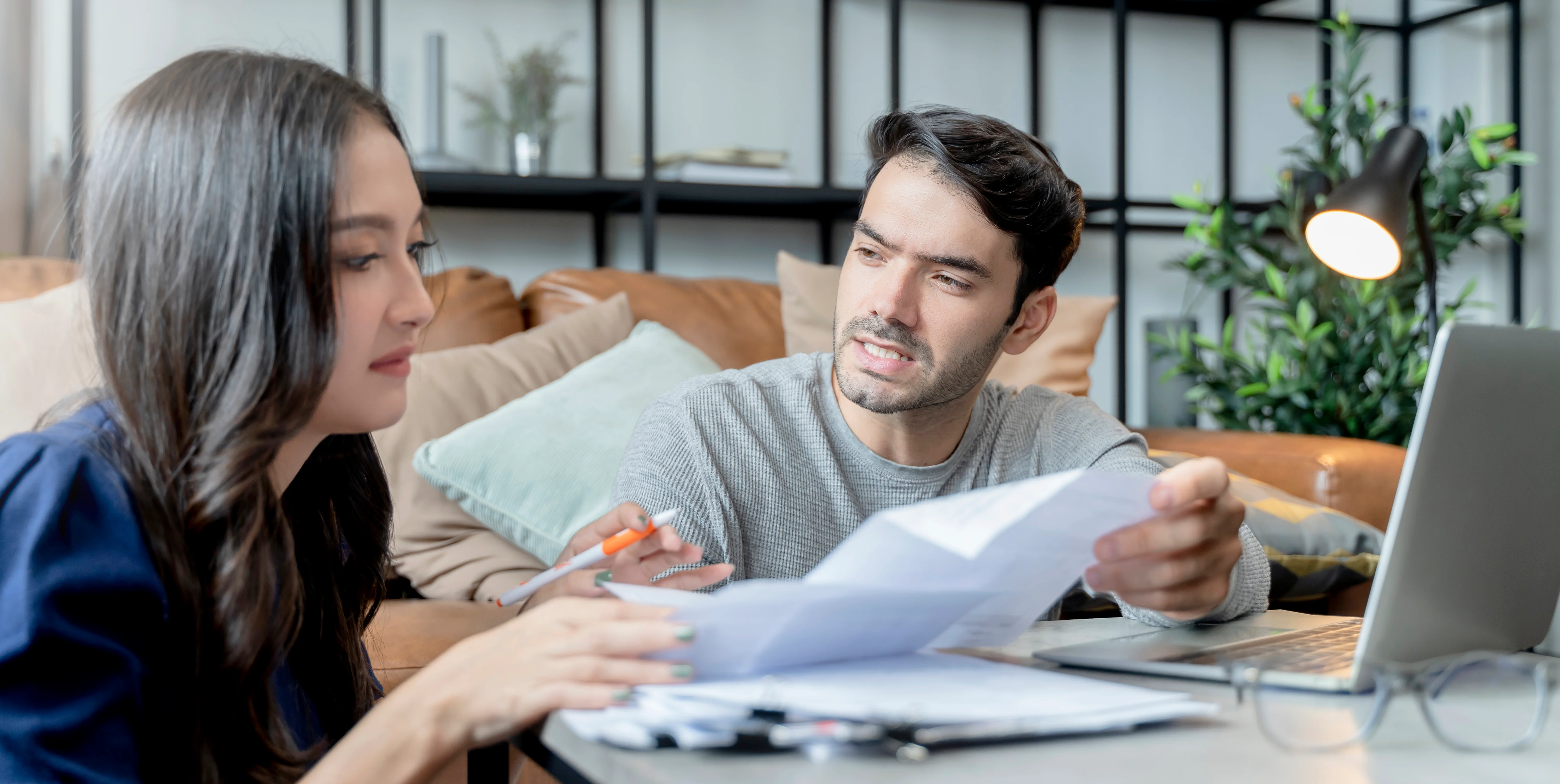 Couple reviewing household bills and financial documents while discussing healthcare costs and tax planning