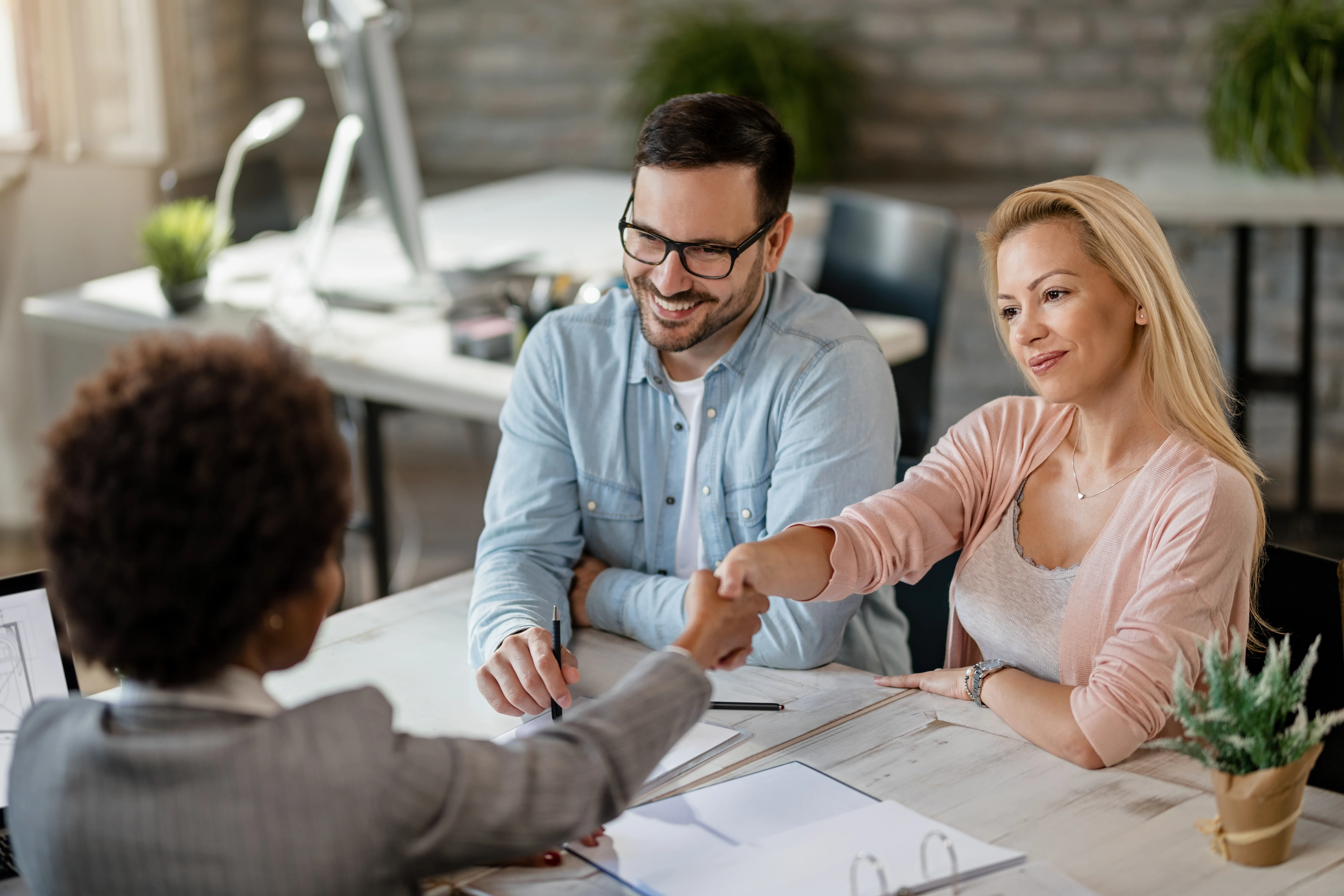 Couple shaking hands and speaking with insurance broker Couple shaking hands and speaking with insurance broker