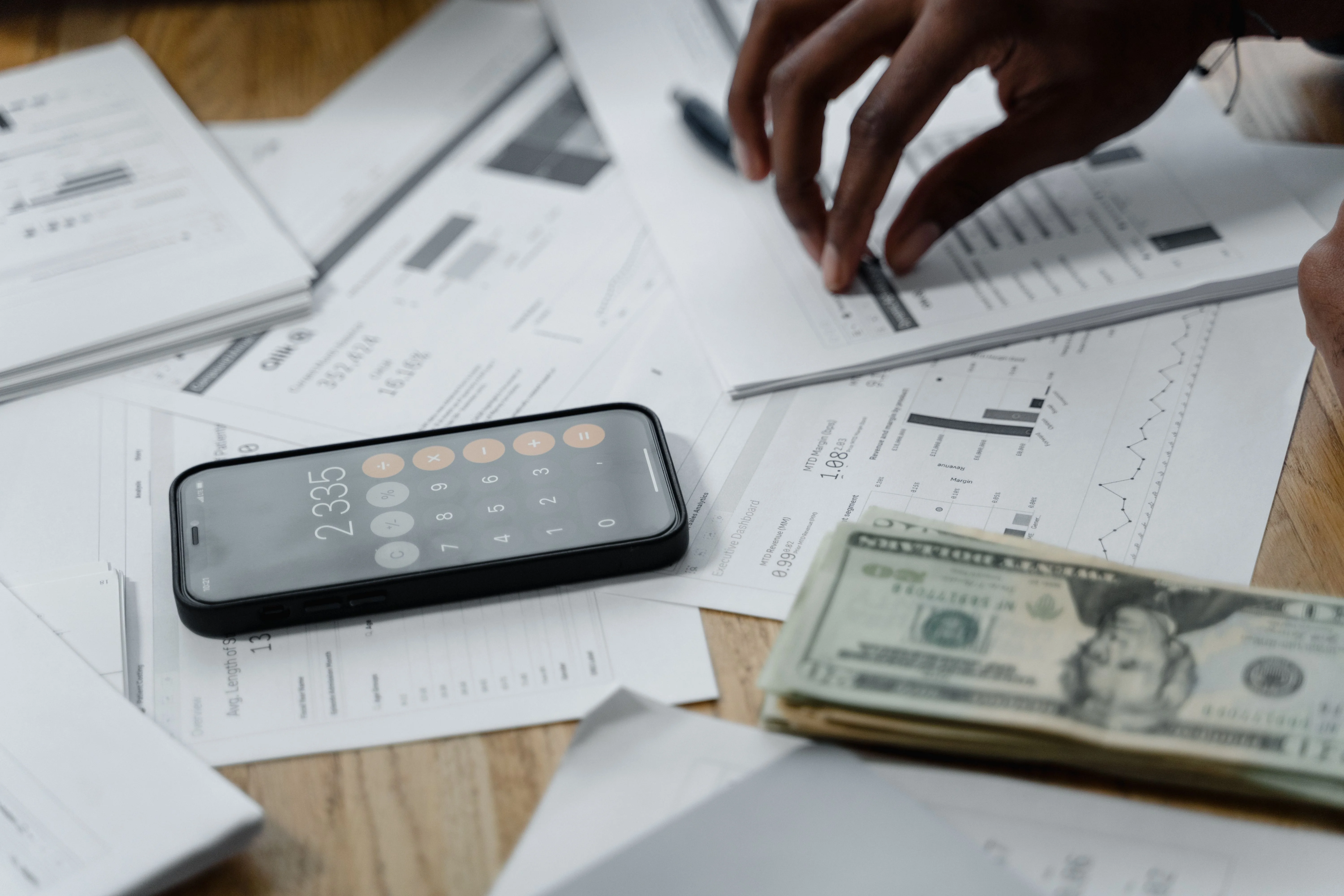 Financial documents, cash and smartphone calculator used to review tax expenses and high income earner tax strategies