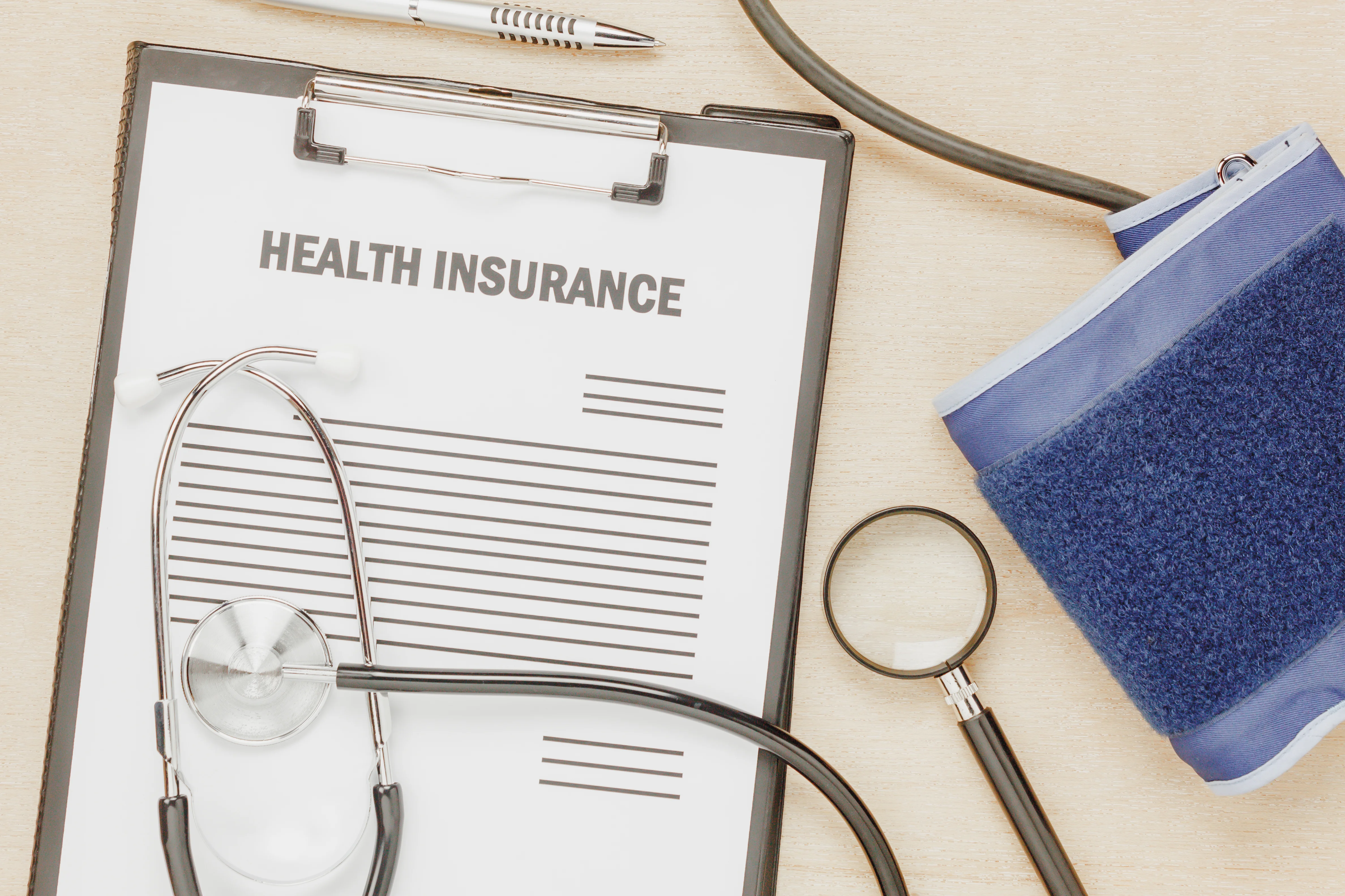health insurance form on clipboard with stethoscope and blood pressure cuff