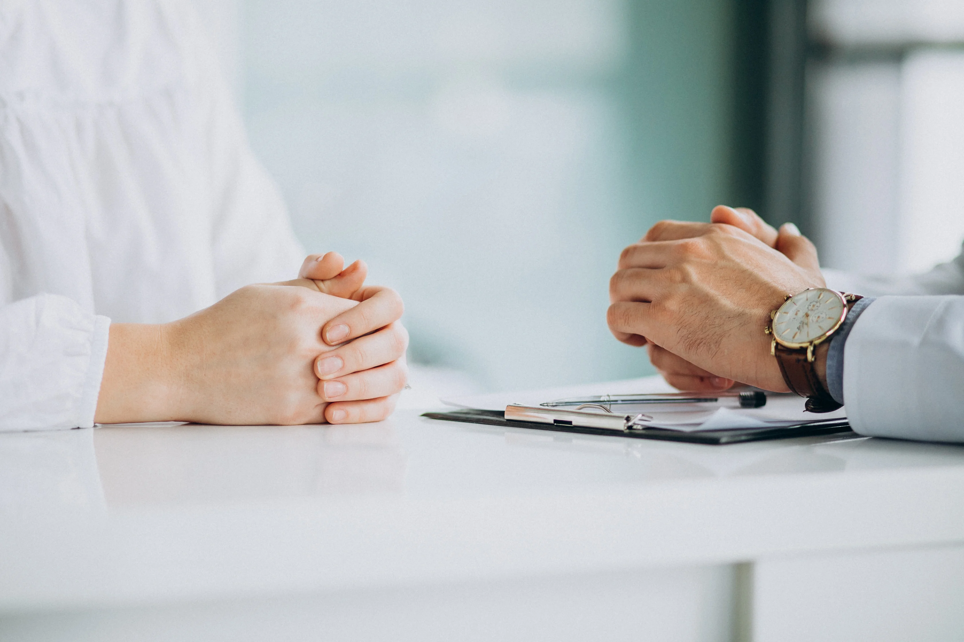 Insurance advisor discussing options with client at table with hands folded