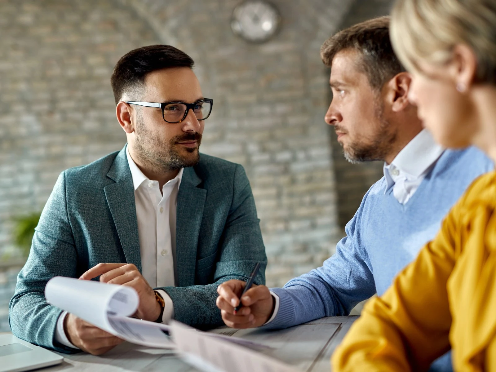 Insurance agent offering agreement to couple for signing during office meeting