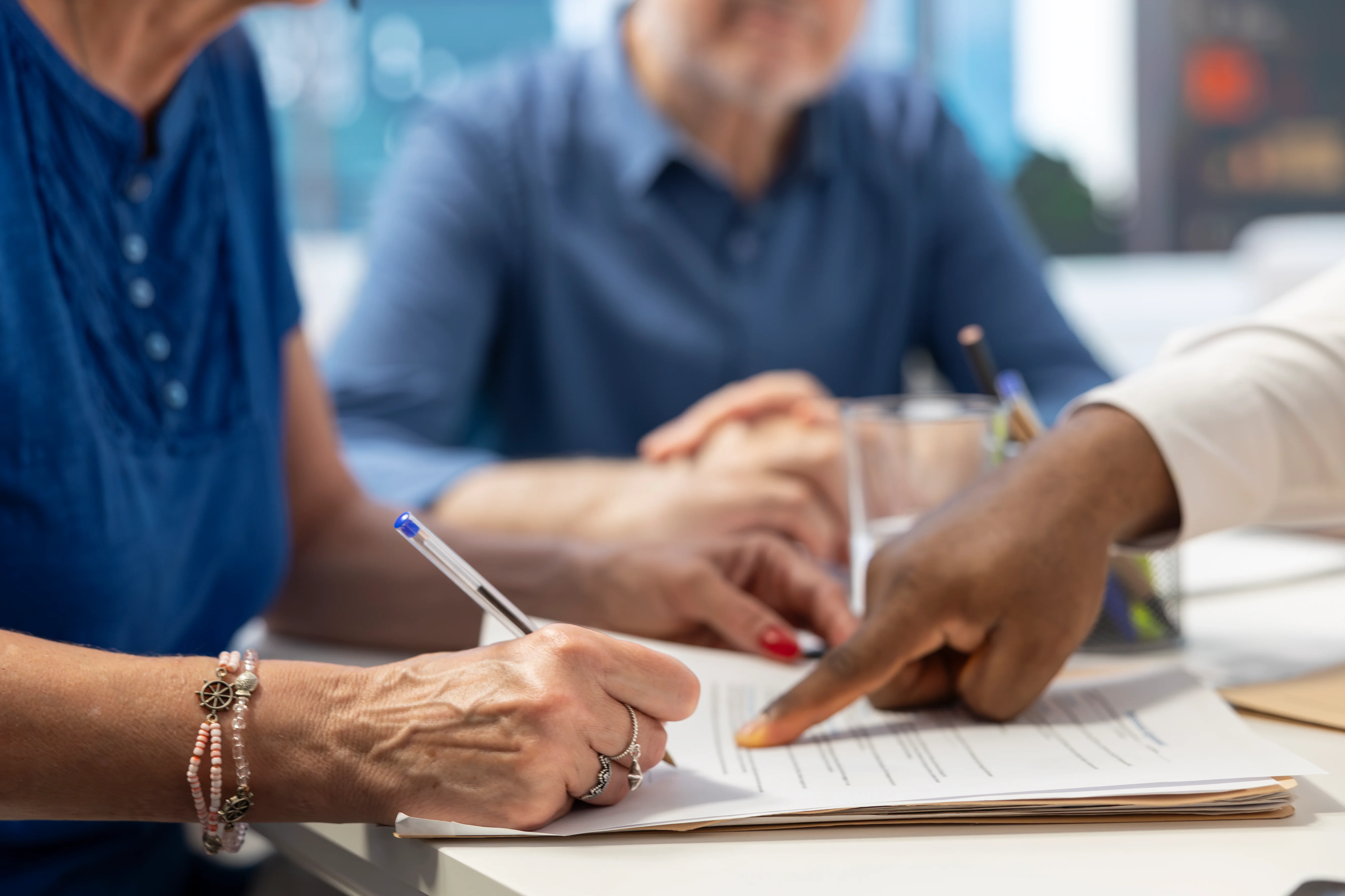 Insurance broker pointing to client where to sign insurance paperwork