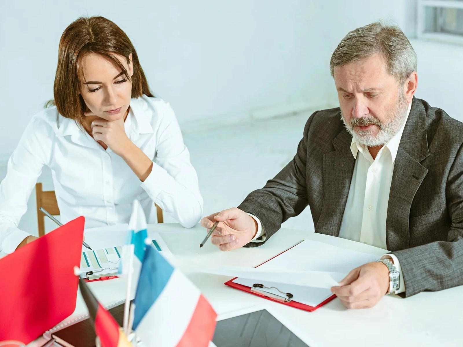 Man and woman reviewing documents together at desk with flags