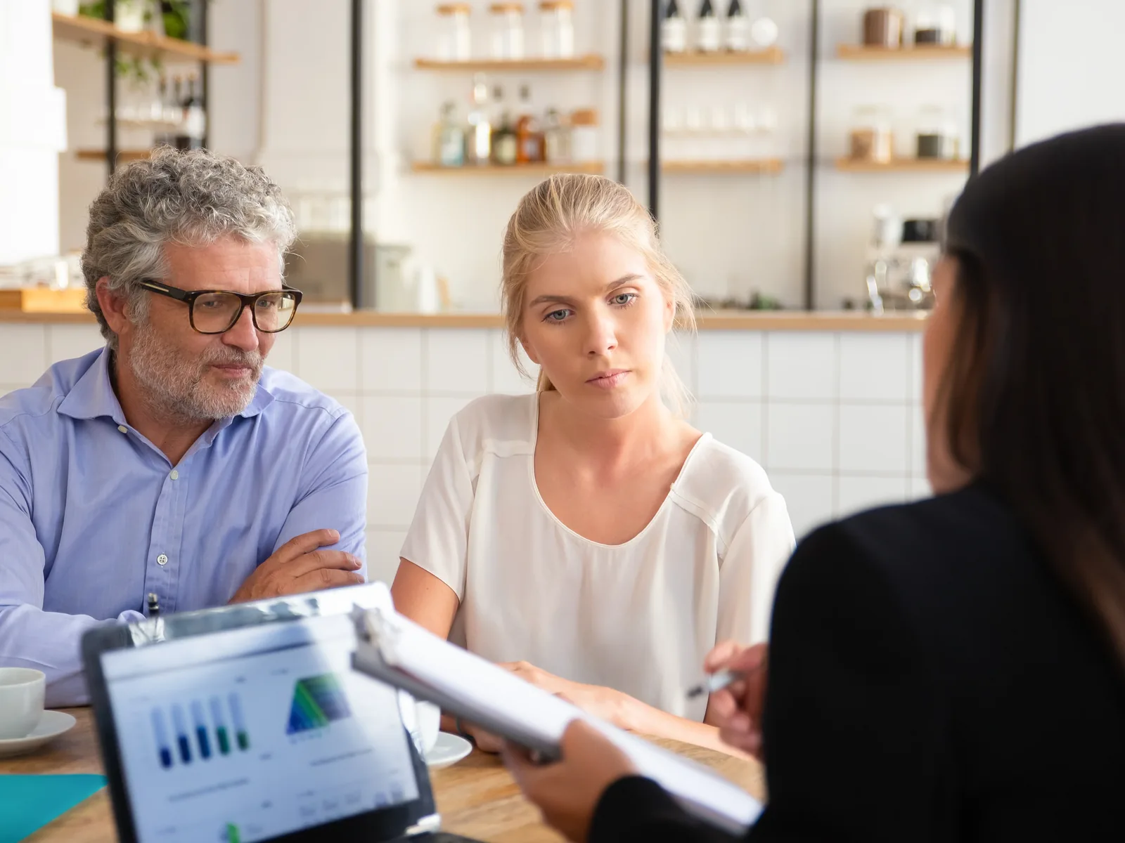 Middle aged man and young woman meeting insurance agent with tablet and charts