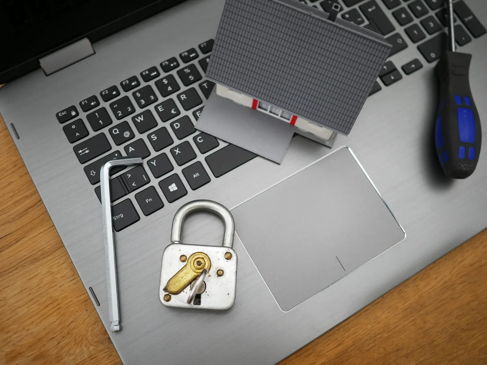 Padlock and model house on laptop keyboard home security concept