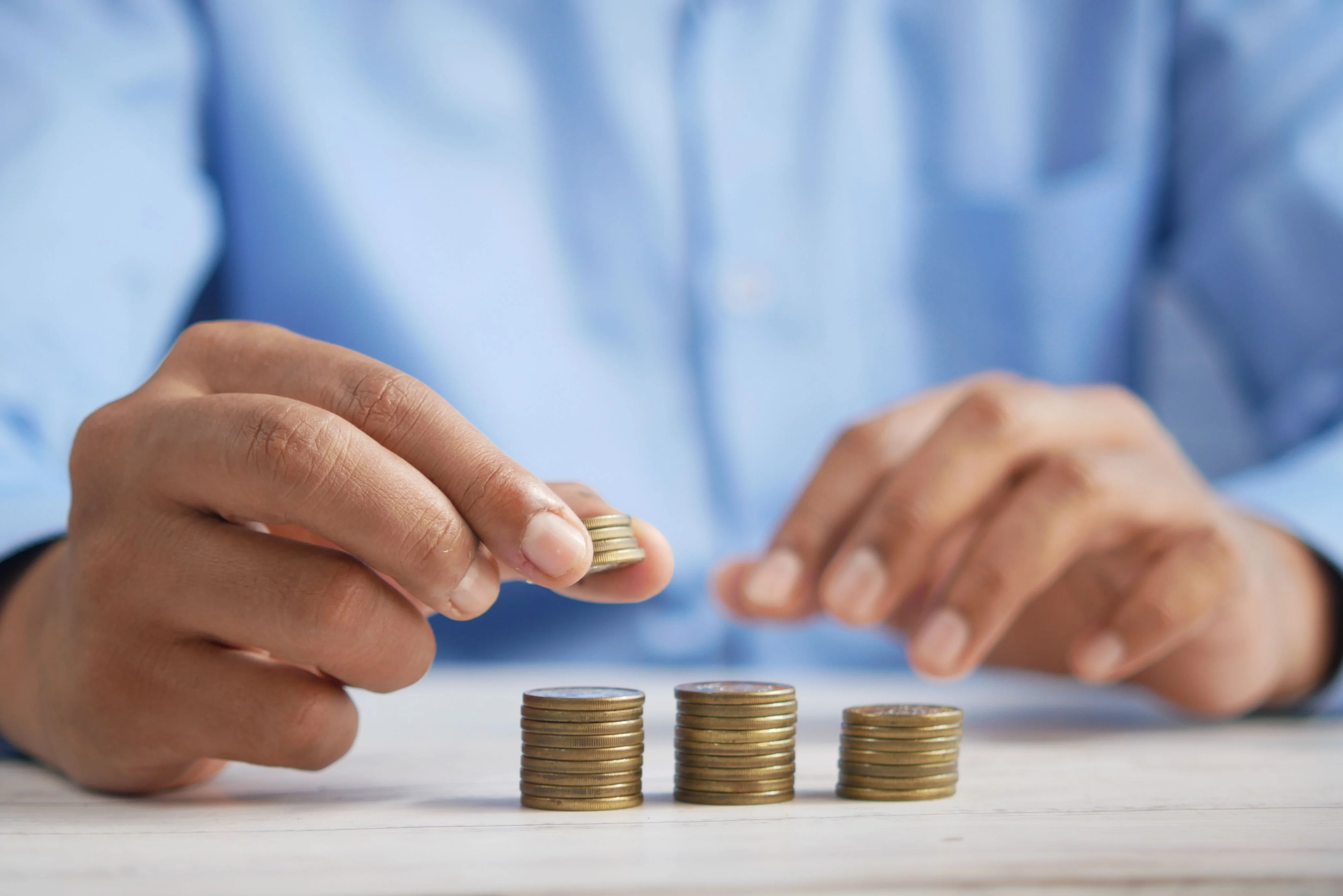 Person stacking coins to represent financial savings for high income earners