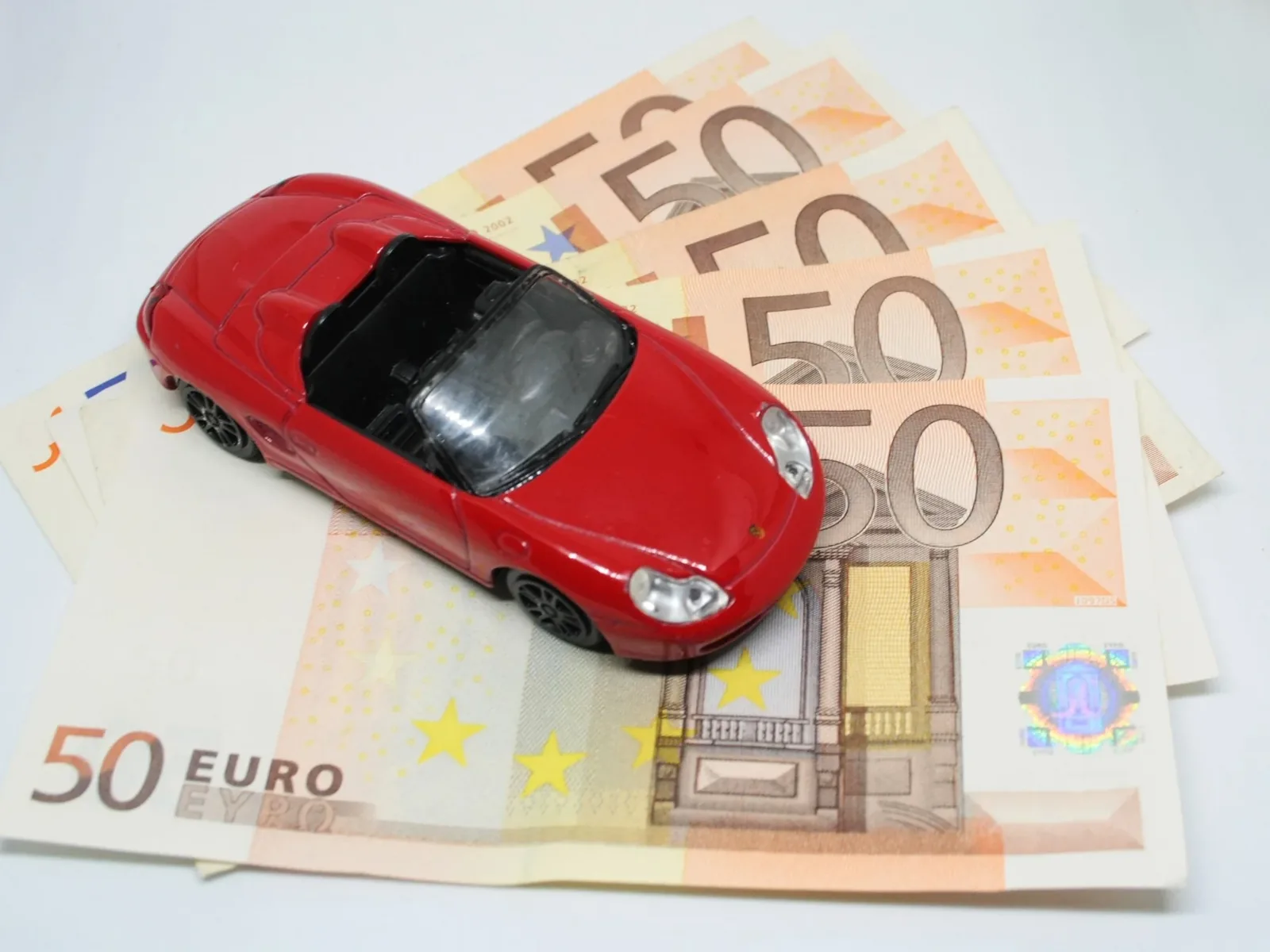 Red toy car on stack of money for federal poverty limit