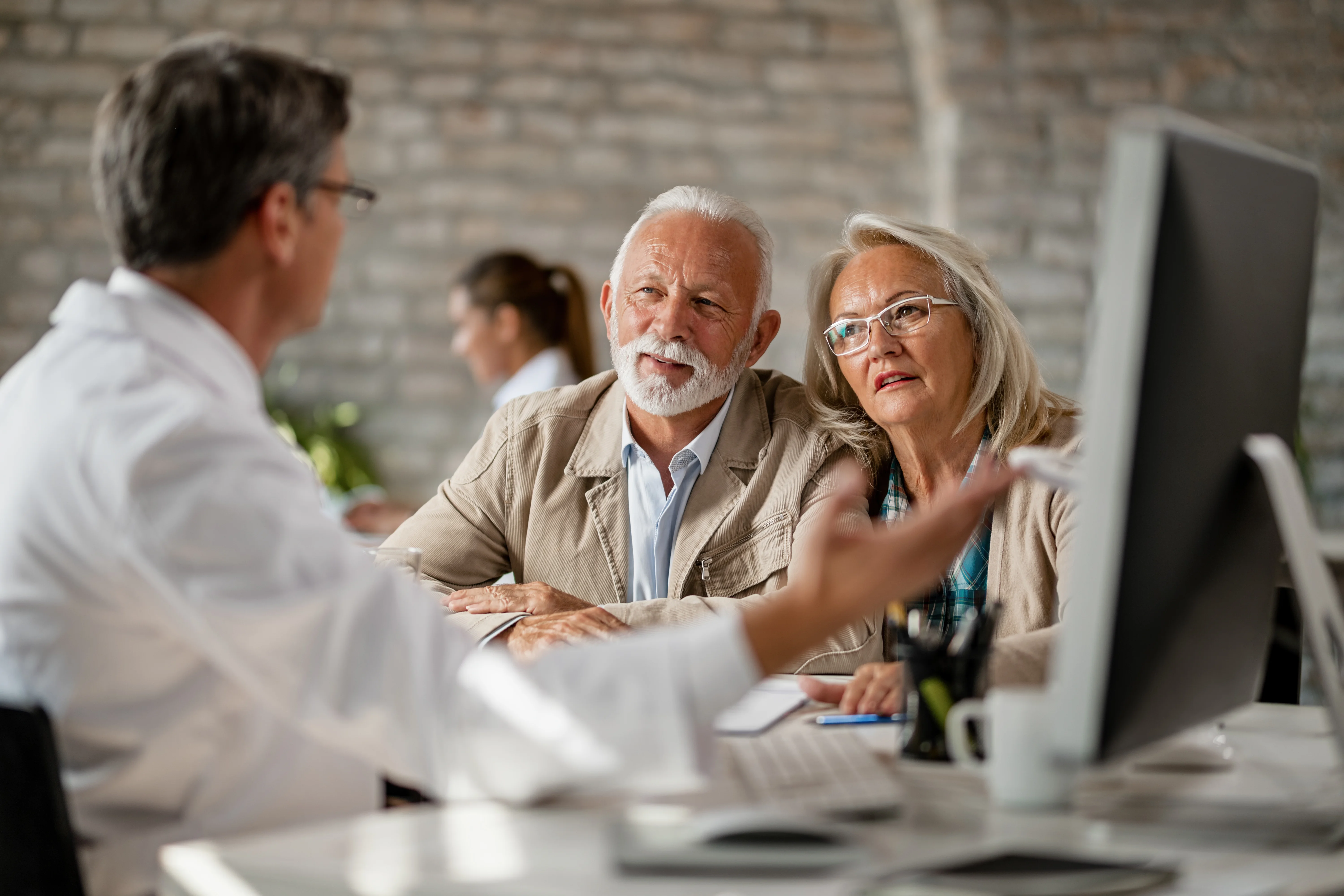 senior couple discussing medical records and health insurance with doctor at clinic
