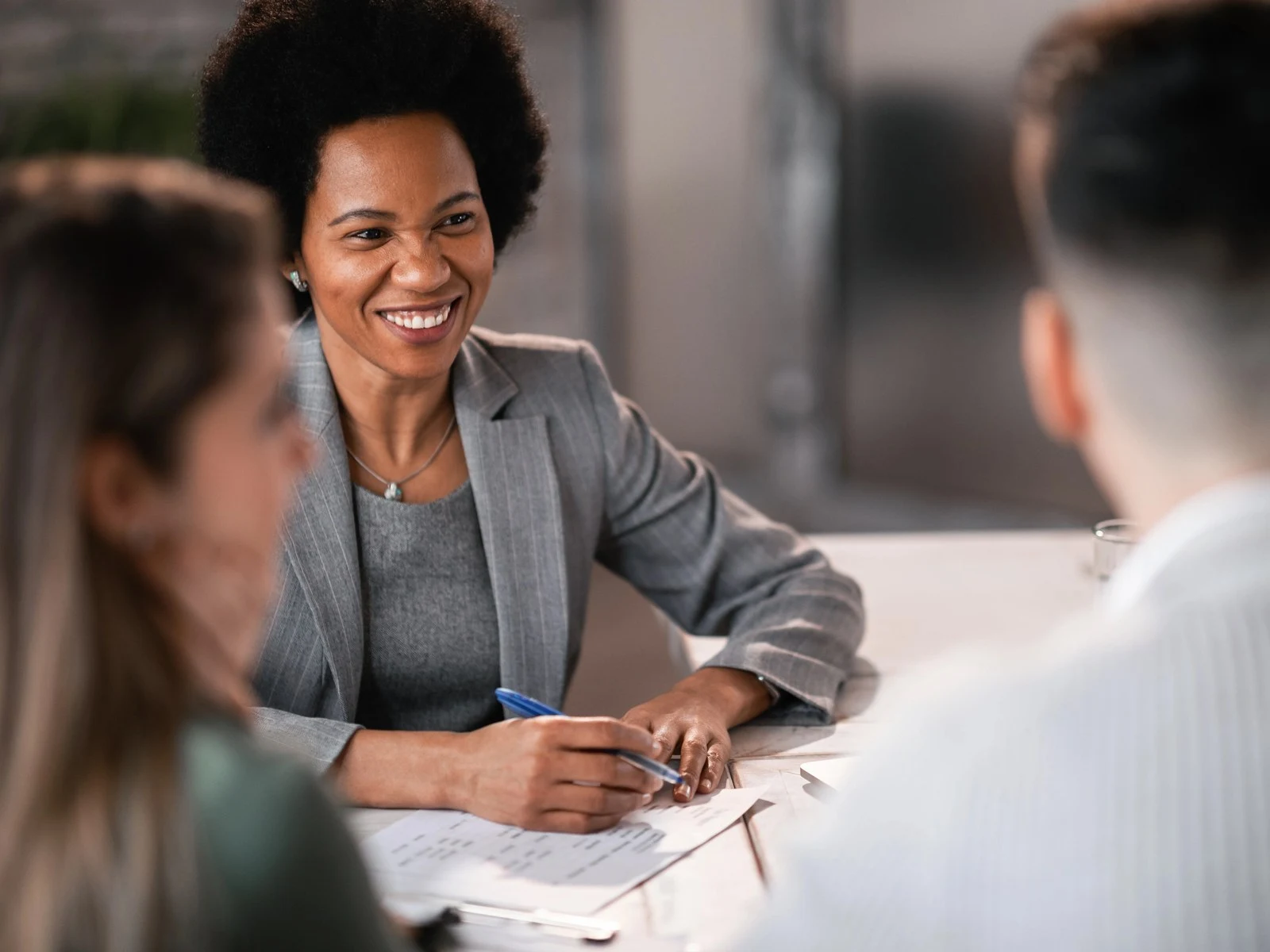 Smiling financial advisor taking notes during consultation with couple
