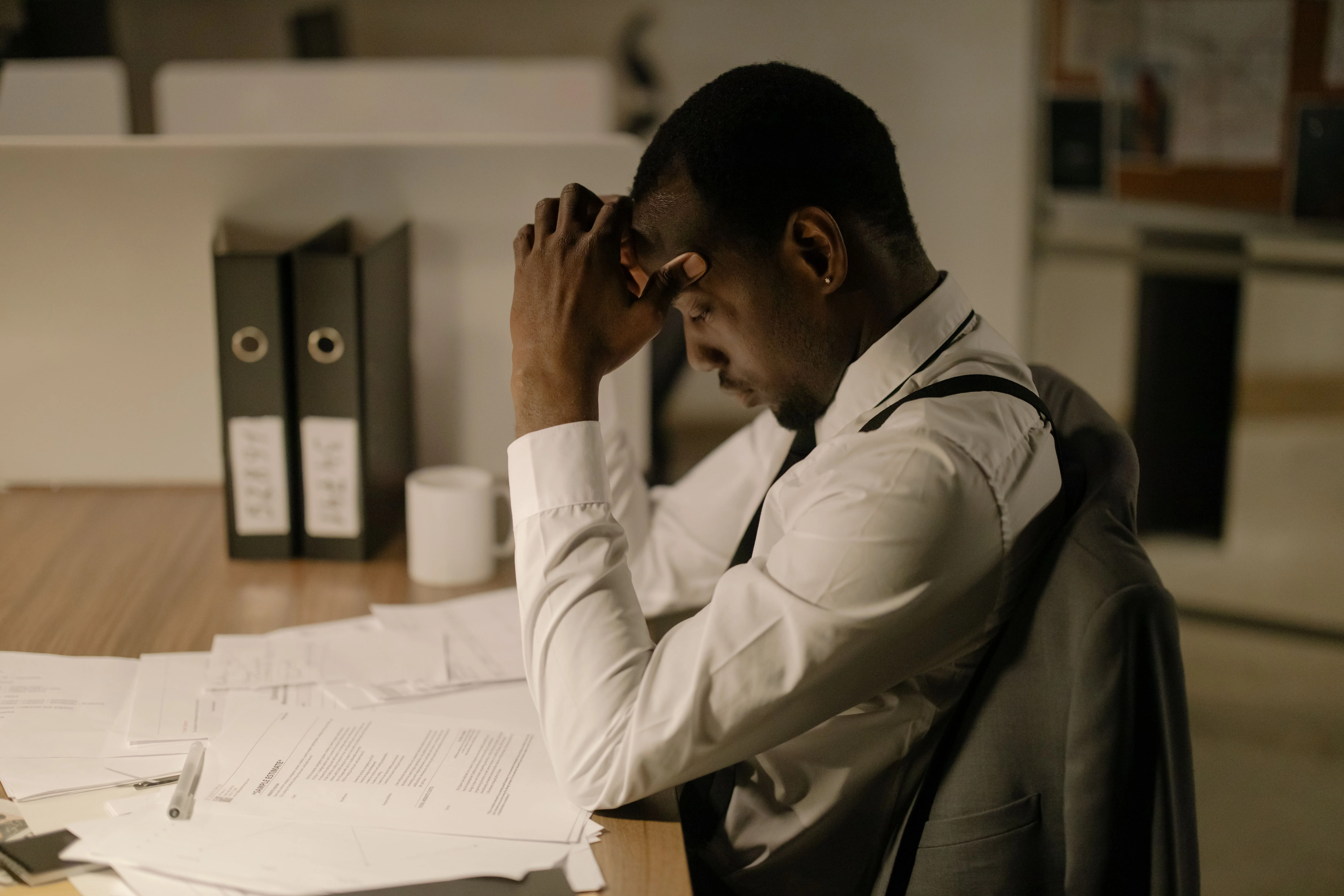 Stressed businessman reviewing financial paperwork and expenses at his office desk