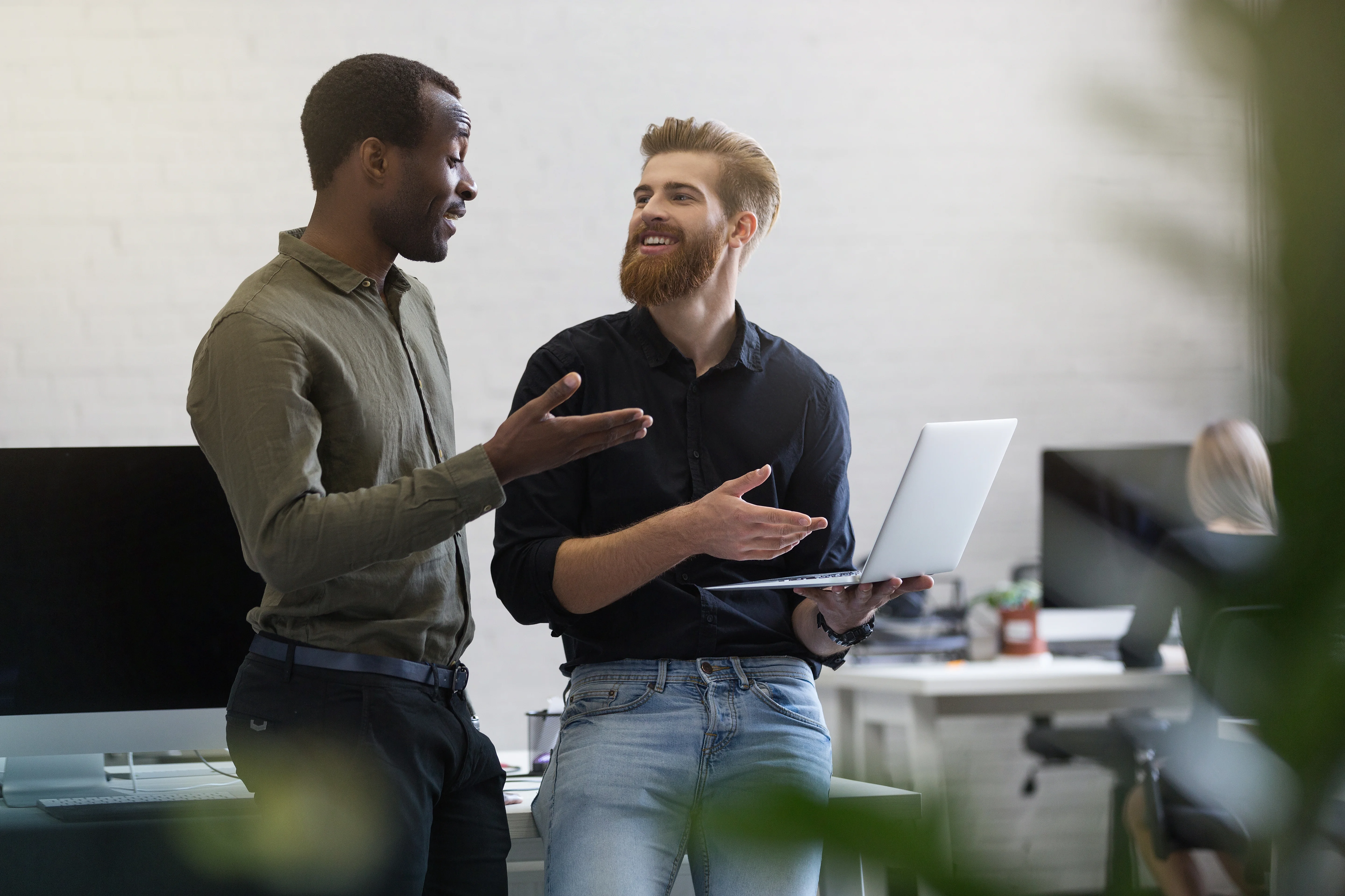 two coworkers having health insurance discussion with laptop in office