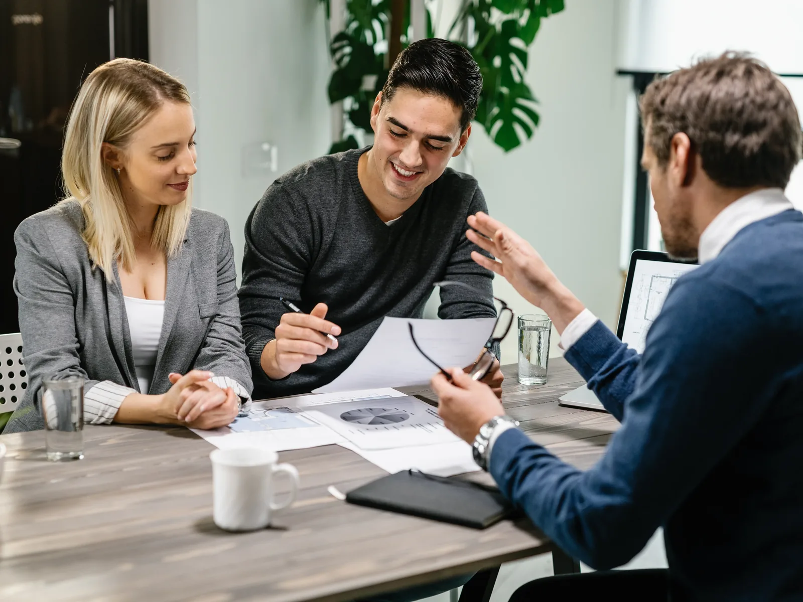 Young couple reviewing documents with advisor during meeting at home